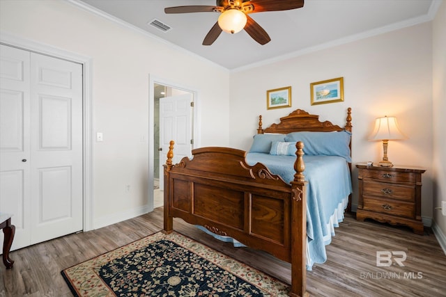 bedroom with baseboards, wood finished floors, visible vents, and crown molding