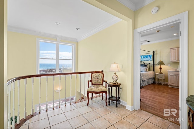 sitting room with light tile patterned flooring, crown molding, baseboards, and a water view