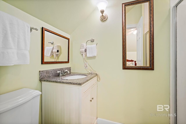 bathroom featuring lofted ceiling, vanity, and toilet