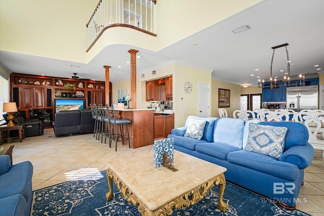 living area with light tile patterned floors, decorative columns, visible vents, a high ceiling, and crown molding