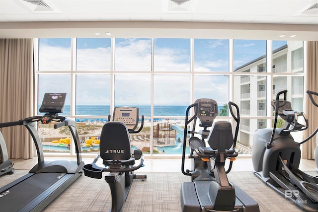 workout area featuring a paneled ceiling and a water view