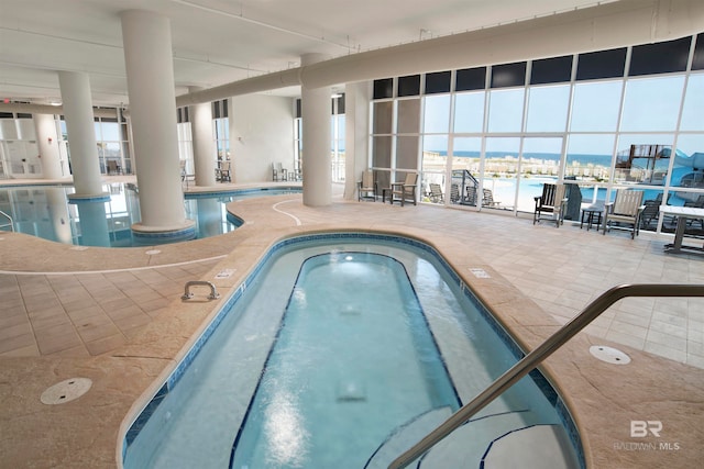 view of pool with a water view, a patio, and a hot tub