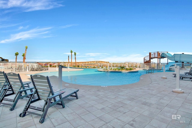 view of pool with a water slide and a patio