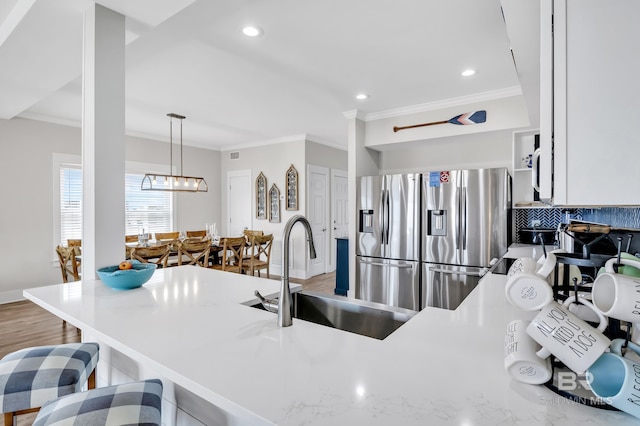 kitchen featuring ornamental molding, recessed lighting, light wood-style flooring, stainless steel refrigerator with ice dispenser, and a sink