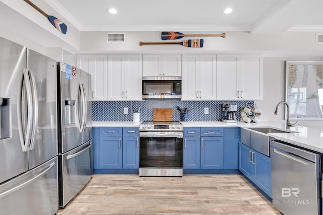 kitchen featuring visible vents, appliances with stainless steel finishes, blue cabinets, and crown molding