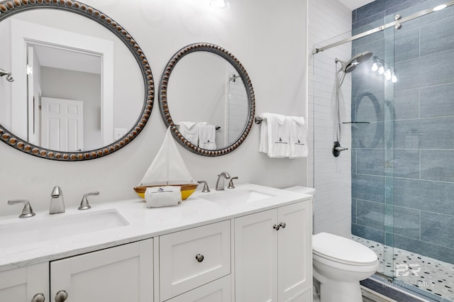 full bathroom featuring double vanity, toilet, a stall shower, and a sink