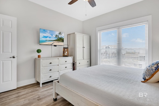 bedroom with a ceiling fan, light wood-style floors, and baseboards