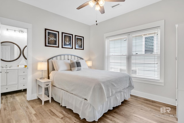 bedroom with ensuite bathroom, baseboards, and light wood finished floors