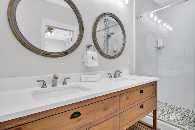 full bathroom with a tile shower, double vanity, and a sink