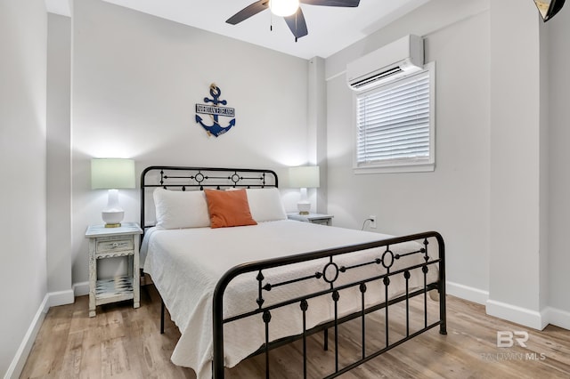 bedroom with baseboards, a wall unit AC, and wood finished floors