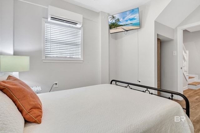 bedroom featuring a wall mounted air conditioner and wood finished floors