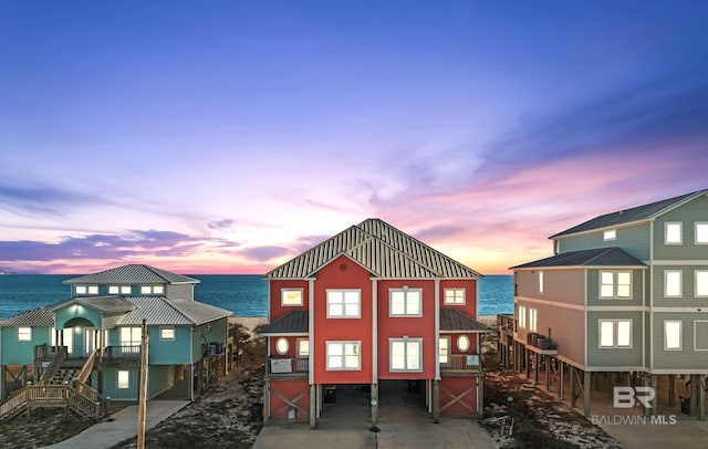 exterior space featuring a water view, driveway, a barn, a carport, and stairs