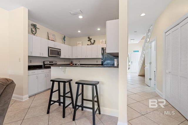 4615 Nancy Ln Unit 8, Orange Beach, AL 36561 - kitchen with a breakfast bar, stainless steel appliances, white cabinets, light tile patterned flooring, and kitchen peninsula