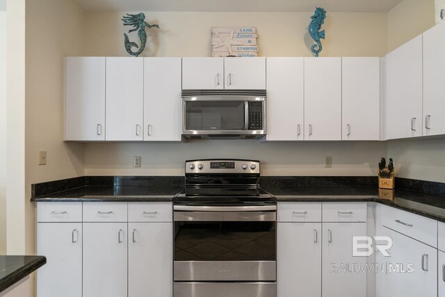 4615 Nancy Ln Unit 8, Orange Beach, AL 36561 - kitchen featuring dark stone countertops, appliances with stainless steel finishes, and white cabinets