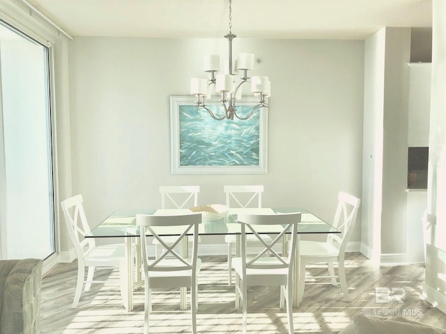 dining area with light wood-type flooring and an inviting chandelier