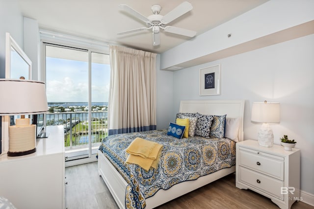 bedroom featuring a water view, wood-type flooring, access to outside, and multiple windows