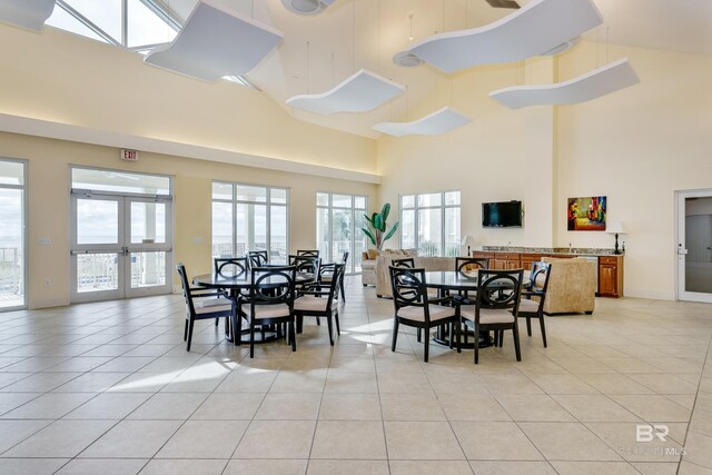 dining space with a towering ceiling and light tile patterned flooring