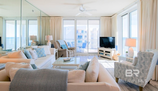 living room with ceiling fan, expansive windows, and light hardwood / wood-style floors