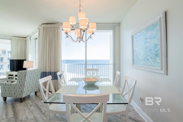 dining space with a notable chandelier, a water view, and wood-type flooring