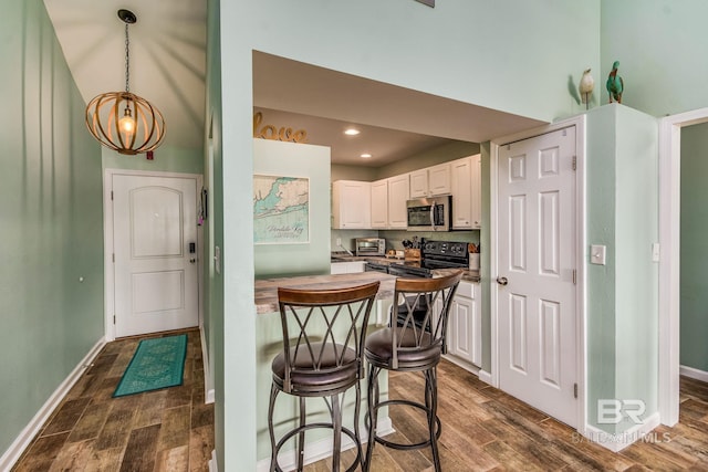 kitchen with black electric range, dark hardwood / wood-style flooring, decorative light fixtures, and white cabinets