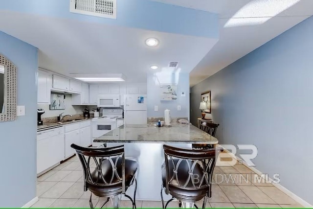 kitchen featuring sink, white appliances, white cabinets, and a kitchen bar