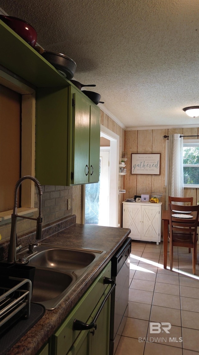 kitchen with a textured ceiling, dishwasher, light tile patterned floors, green cabinets, and sink