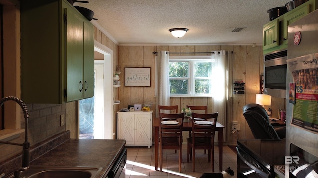 dining room featuring light tile patterned floors, wood walls, a textured ceiling, and sink