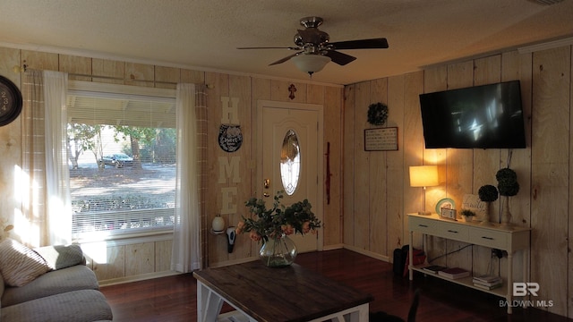 living room with ceiling fan, dark hardwood / wood-style flooring, and wooden walls