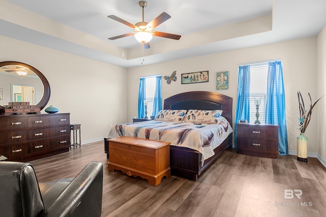 bedroom with wood-type flooring, a tray ceiling, and ceiling fan