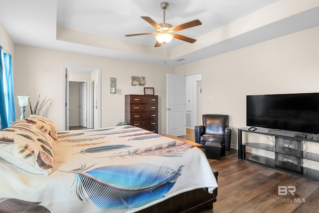 bedroom with a tray ceiling, ceiling fan, and dark hardwood / wood-style flooring