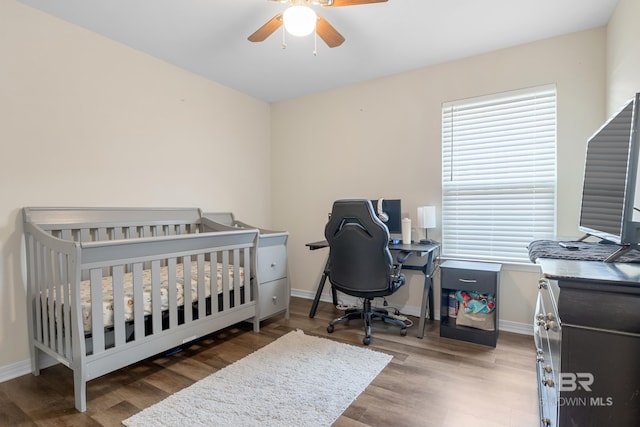 bedroom with ceiling fan, dark wood-type flooring, and a crib