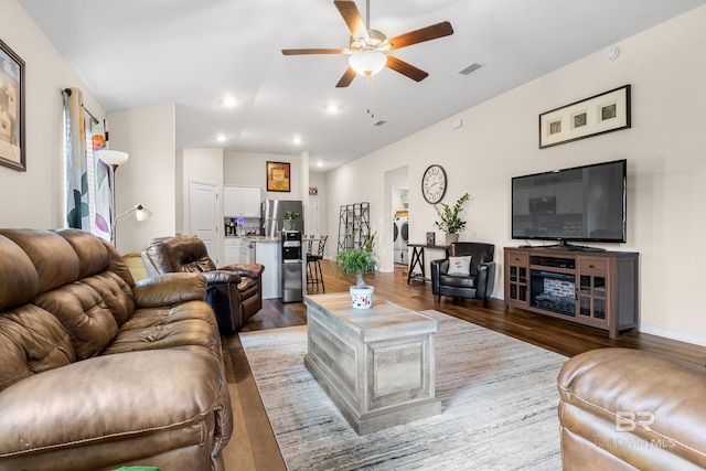 living room featuring hardwood / wood-style flooring, ceiling fan, washer / dryer, and lofted ceiling