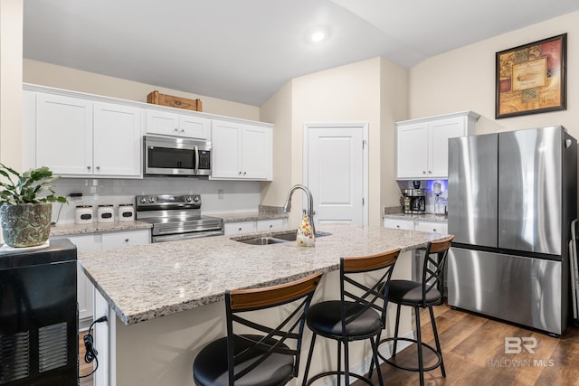 kitchen featuring white cabinets, sink, stainless steel appliances, and an island with sink