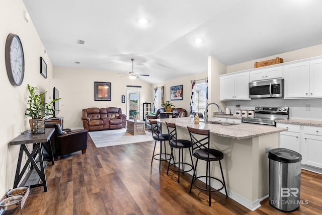 kitchen featuring a breakfast bar area, white cabinets, an island with sink, and appliances with stainless steel finishes