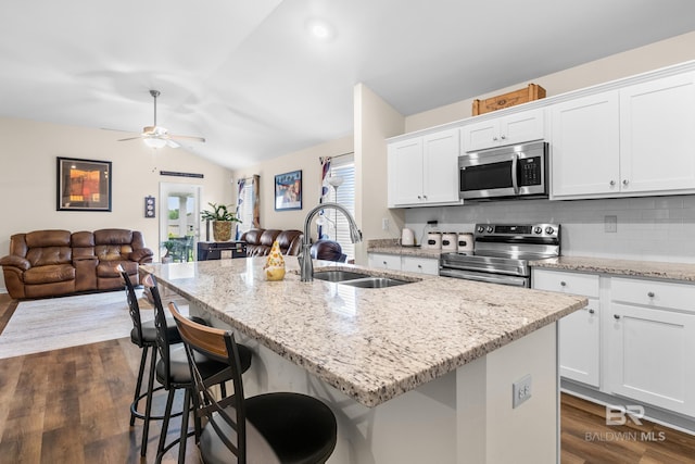 kitchen with decorative backsplash, stainless steel appliances, sink, a center island with sink, and white cabinetry