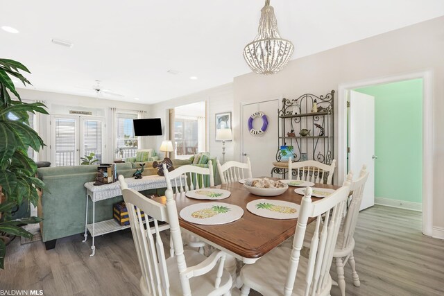dining space featuring ceiling fan with notable chandelier and light hardwood / wood-style flooring