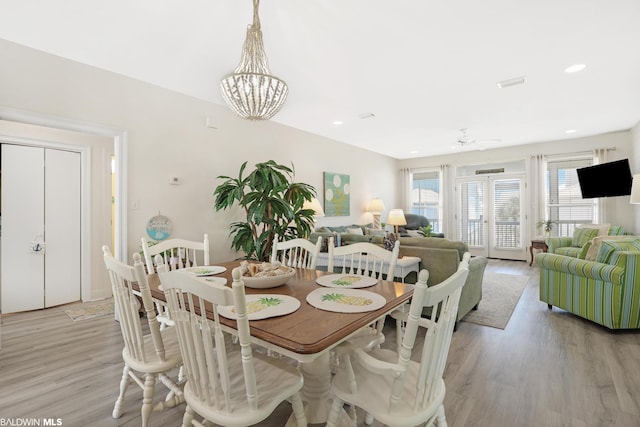 dining room featuring light wood-type flooring and ceiling fan with notable chandelier