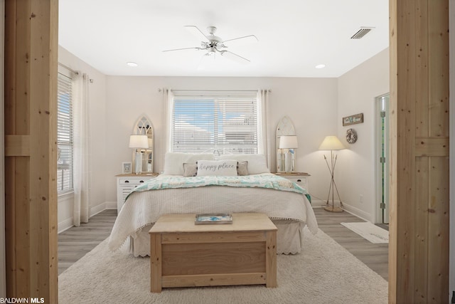 bedroom featuring ceiling fan, light wood-type flooring, and multiple windows