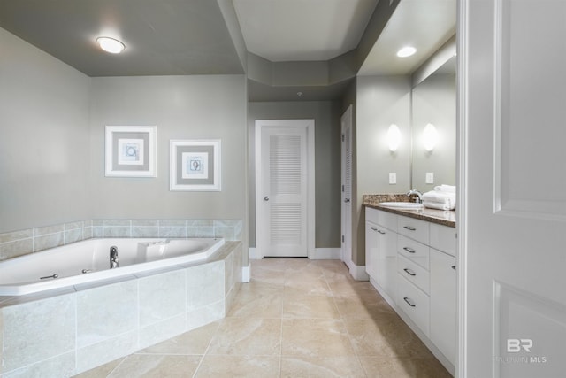 bathroom with tile patterned flooring, vanity, and a relaxing tiled tub