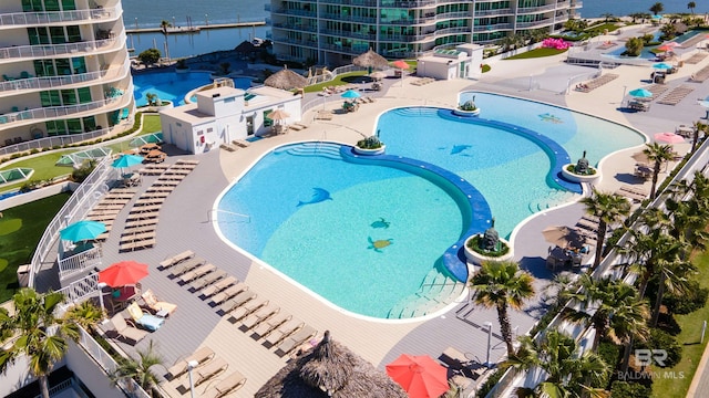 view of pool with a jacuzzi, a water view, and a patio area