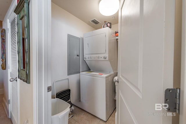 washroom with stacked washer / dryer and light tile flooring