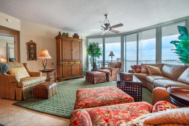 tiled living room featuring ceiling fan, a textured ceiling, and expansive windows