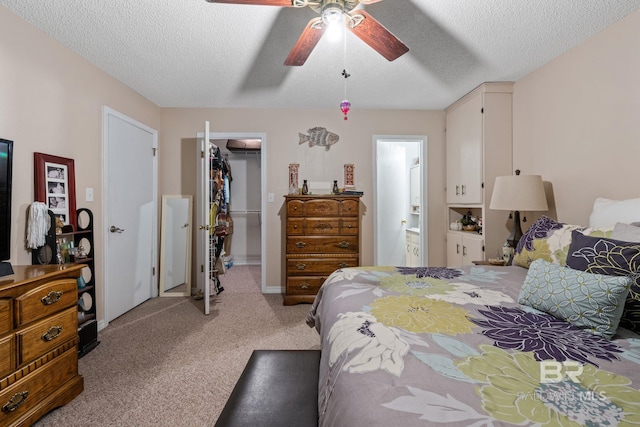 carpeted bedroom with a closet, ceiling fan, ensuite bathroom, and a textured ceiling