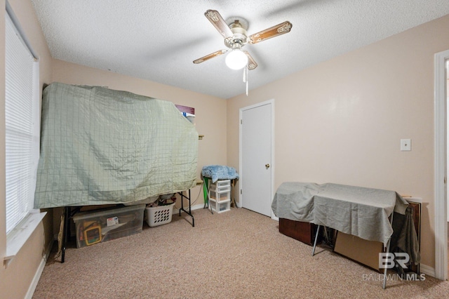 carpeted bedroom featuring ceiling fan and a textured ceiling