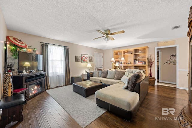 living room with a textured ceiling, ceiling fan, and dark hardwood / wood-style flooring