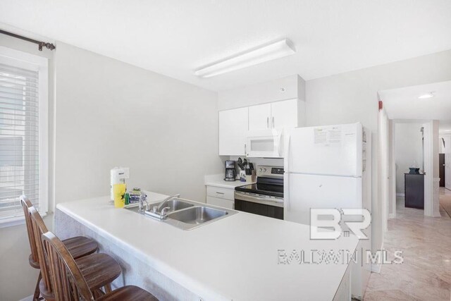561 E Beach Blvd Unit 208, Gulf Shores, AL 36542 - kitchen featuring a kitchen breakfast bar, a sink, a peninsula, white appliances, and white cabinetry