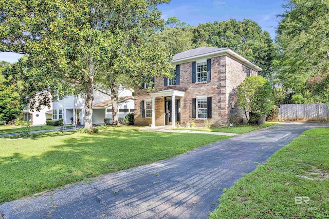 view of front of property with a front yard, brick siding, and fence