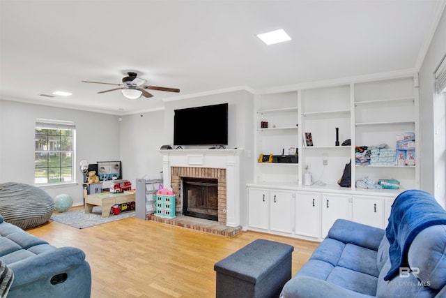 living room featuring ceiling fan, a fireplace, light hardwood / wood-style floors, and ornamental molding