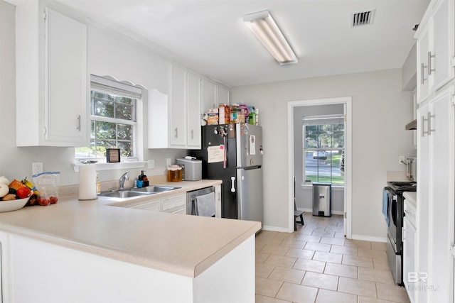 kitchen with sink, plenty of natural light, light tile patterned floors, stainless steel appliances, and kitchen peninsula