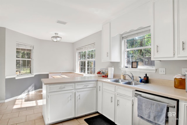 kitchen featuring a wealth of natural light, kitchen peninsula, stainless steel dishwasher, and light tile patterned flooring